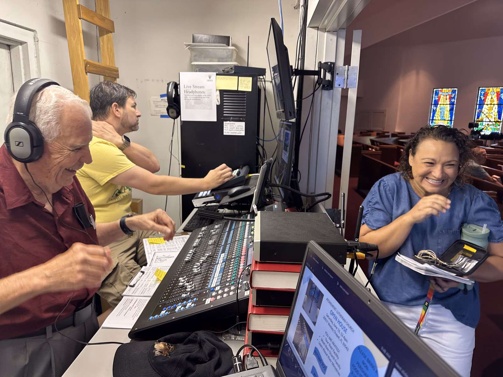 Volunteers working the sound board and livestream laptop in the audio-visual booth at the back of the Sanctuary